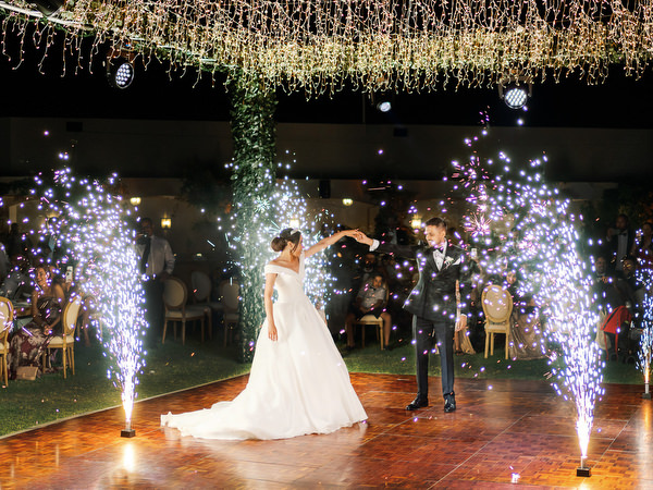 Couple dancing under lights during Athens Riviera wedding party with fireworks