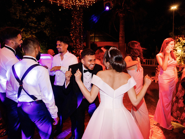 Bride and groom dancing together surrounded by guests