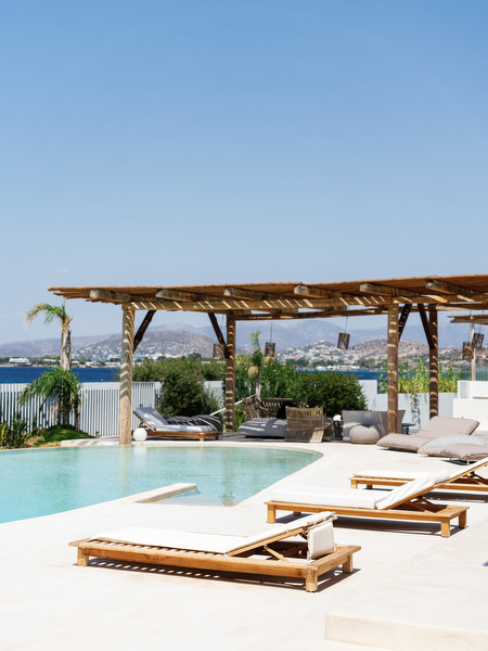 Luxury villa pool overlooking the Athens Riviera coastline with wooden pergola lounge area and sunbeds