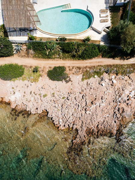 Aerial view of private seaside villa on the Athens Riviera with infinity pool and rocky coastline