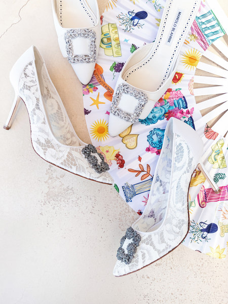 Bridal detail flat lay with embellished lace wedding heels and colorful Mediterranean-inspired stationery