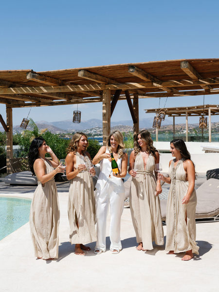 Stylish bridesmaids laughing poolside under wooden pergola at Riviera wedding venue