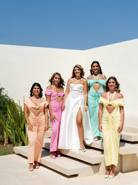 Bride and bridesmaids in bold pastel Greco-Disco gowns descending modern villa steps in Athens