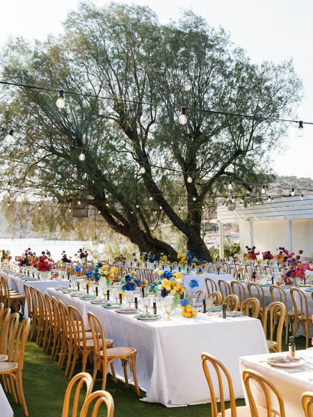 Elegant banquet table beneath large tree overlooking the Athens Riviera coastline