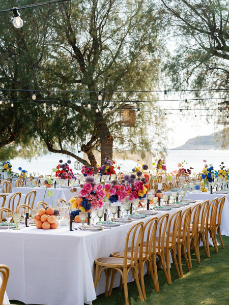 Long banquet setup with vibrant florals and sea backdrop at luxury Athens destination wedding