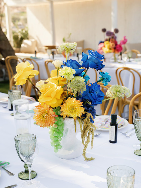 Bold blue and yellow floral arrangement on long reception table by the sea in Athens