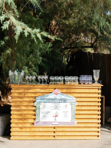 Wooden cocktail bar with custom illustrated signage at luxury Athens Riviera wedding