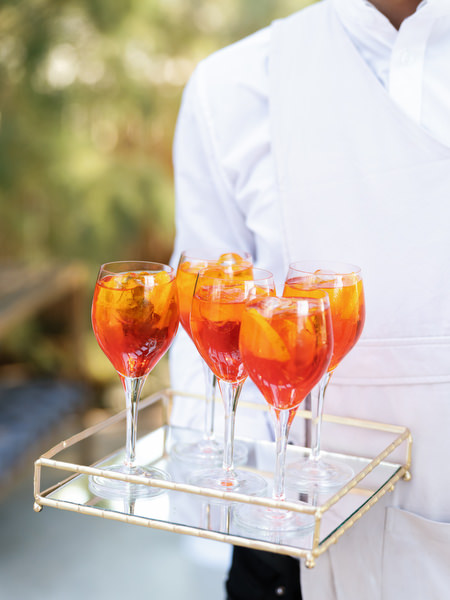 Server carrying tray of bright orange spritz cocktails during Athens destination wedding reception