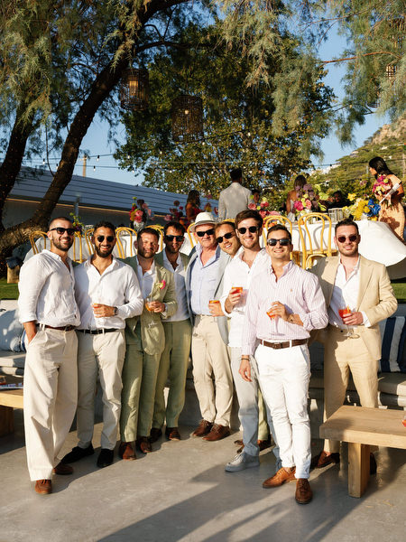 Groom in white suit celebrating with guests during Athens Riviera reception