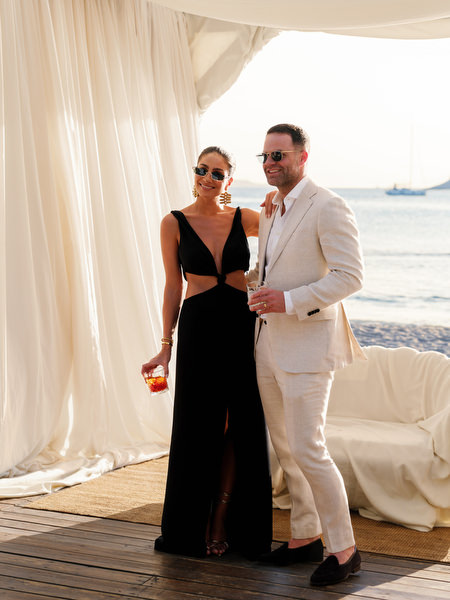 Stylish couple in black and beige attire during seaside cocktail hour on the Athens Riviera