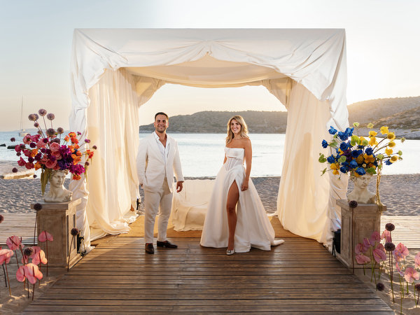 Bride and groom standing beneath white canopy on the beach at Athens Riviera wedding