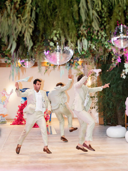 Groomsmen in light suits performing choreographed dance during Athens destination wedding reception