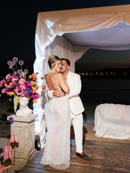 Bride and groom embracing beneath seaside canopy at night during luxury Athens wedding
