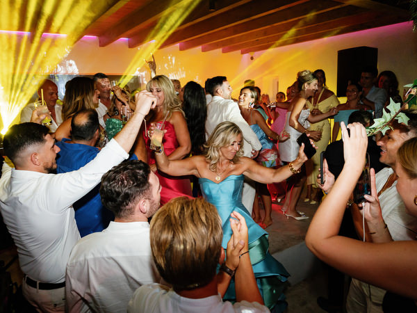 Crowded wedding reception dance floor with dramatic yellow beams of light and energetic celebration atmosphere