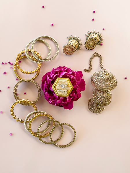 Traditional Indian bridal bangles and gold earrings styled with pink flowers for colourful Hindu wedding in Athens.