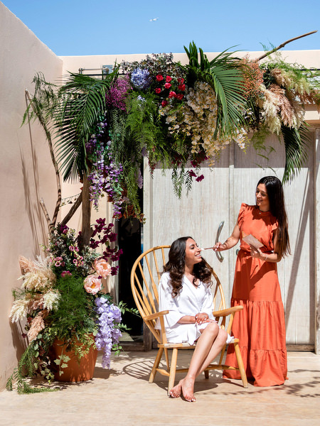 Bride getting ready under lush floral arch at Private House Island Resort Athens Riviera Indian wedding morning.