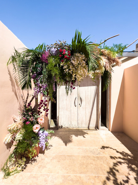 Colourful floral doorway installation with palms and purple blooms at Private House Island Resort Athens Riviera wedding venue.