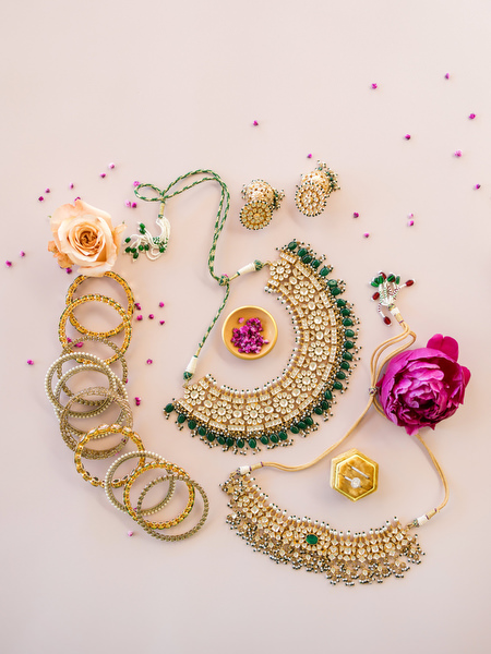 Indian bridal jewellery flatlay with gold necklace, bangles and wedding invitation at Athens Riviera destination wedding.