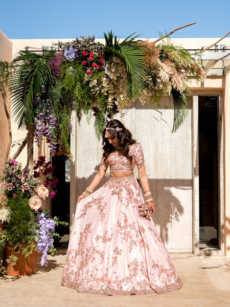 Bride in pink lehenga standing in front of Private House Island Resort Athens Riviera wedding venue.