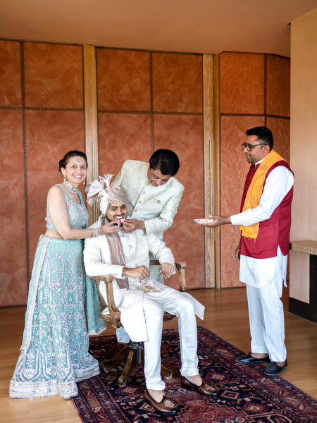 Groom receiving traditional blessing from family during Indian wedding preparations in Athens.