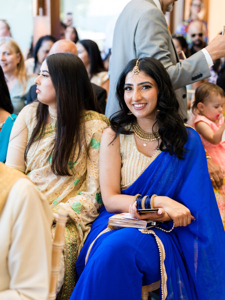 Wedding guest in royal blue sari seated during Indian wedding ceremony at Athens Riviera.