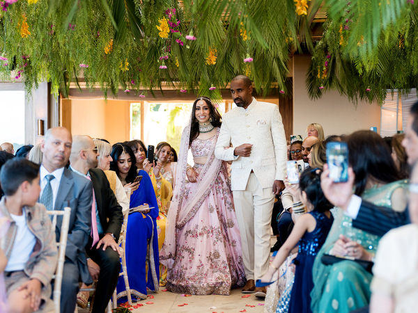 Bride walking down aisle in powder pink lehenga at Private House Island Resort colourful Indian wedding in Athens.