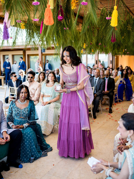 Bridesmaid in purple lehenga walking down aisle during Hindu wedding ceremony at Private House Island Resort Athens.