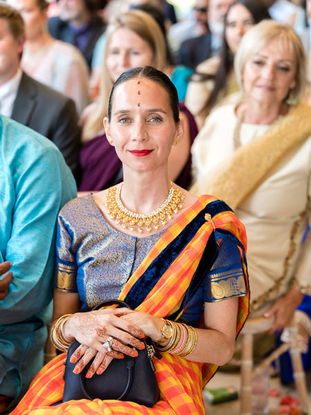 Wedding guest in colourful sari seated during Hindu ceremony at Private House Island Resort Athens Riviera.