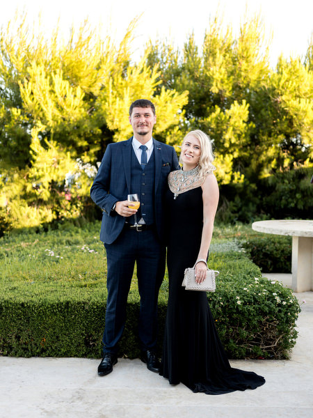 Couple in formal evening wear posing during cocktail hour at Indian destination wedding in Athens Riviera.