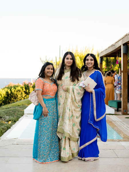 Wedding guests in vibrant blue and gold Indian outfits during Athens Riviera cocktail hour.