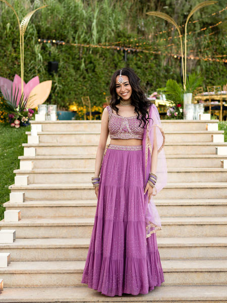 Bridesmaid in purple lehenga posing on staircase at Private House Island Resort Athens Riviera wedding.