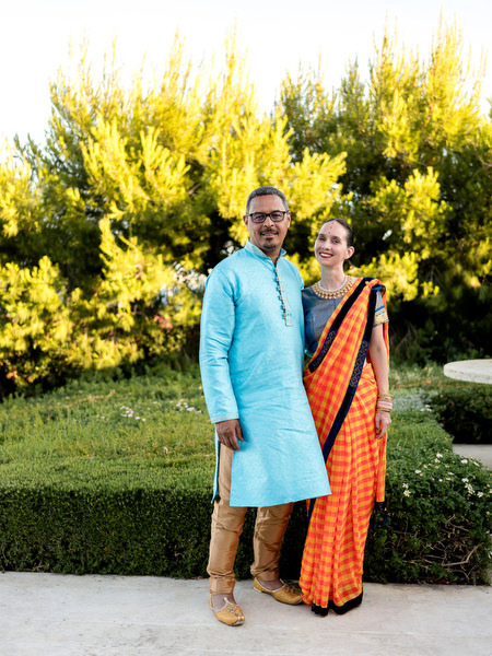 Couple in turquoise kurta and orange sari posing during Indian wedding reception in Athens.