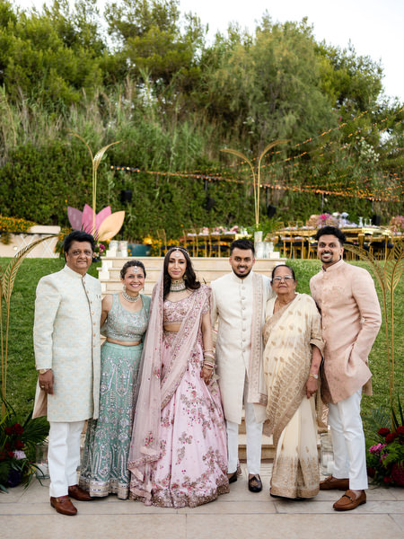 Bride and groom posing with family in coordinated pastel Indian attire at Private House Island Resort Athens Riviera.