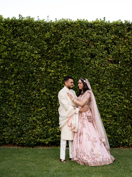 Indian bride and groom posing in front of green hedge at Private House Island Resort Athens.