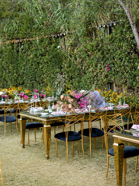 Gold reception tables with pink and purple floral arrangements at Indian wedding in Athens Greece.