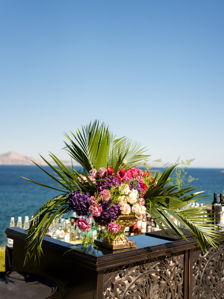 Colourful floral arrangement with palm leaves at seaside Indian wedding reception in Athens.