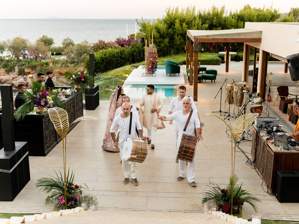 Indian wedding musicians leading reception entrance overlooking the Aegean Sea in Athens.
