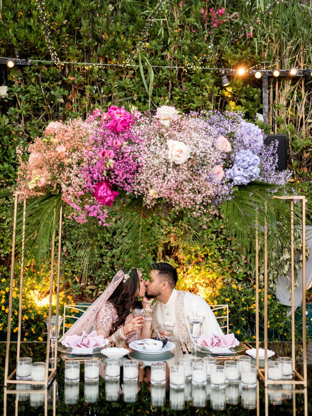 Bride and groom kissing beneath floral canopy at Private House Island Resort Indian destination wedding.