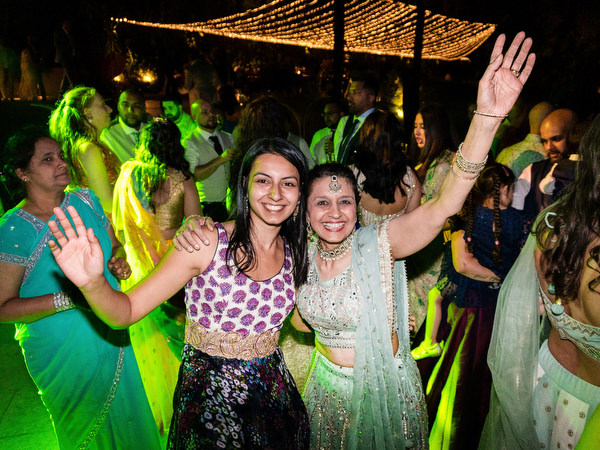 Guests dancing under string lights at Indian destination wedding reception in Greece.