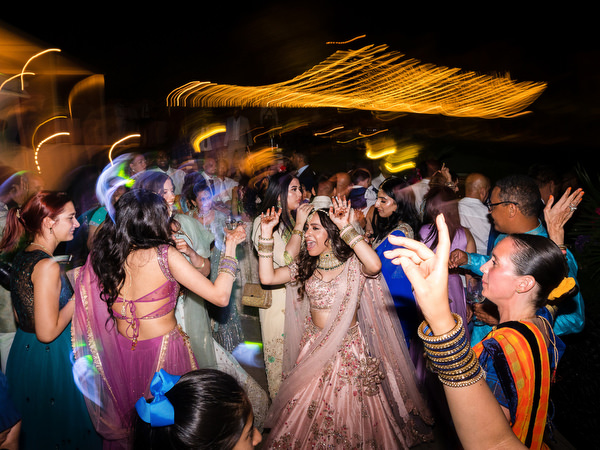 Women in colourful lehengas dancing at Athens Indian wedding reception.