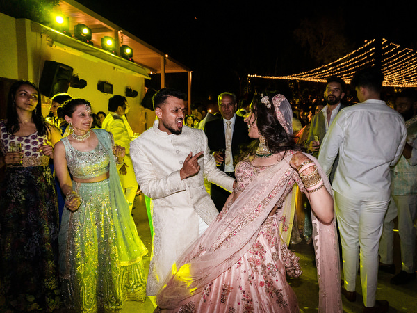 Bride and groom dancing together during high-energy Indian wedding party in Greece.