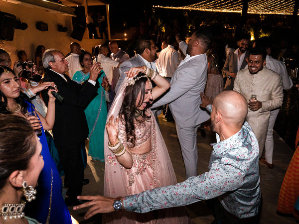 Bride dancing during high-energy Indian wedding party in Greece.