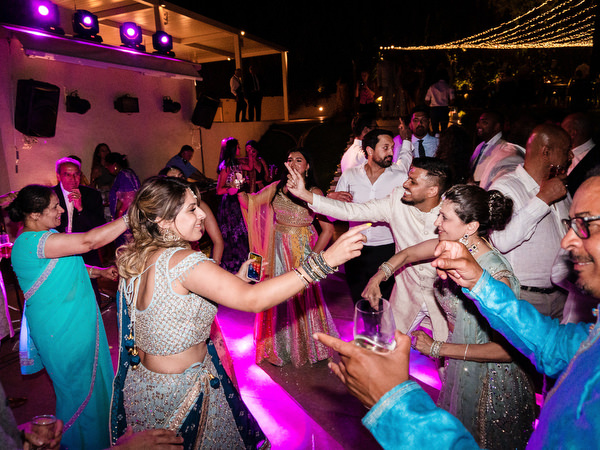 Guests dancing under purple lighting at luxury Indian destination wedding in Athens.