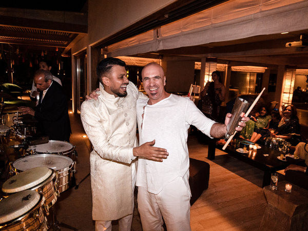 Groom celebrating with live percussionist during Indian wedding reception in Greece.