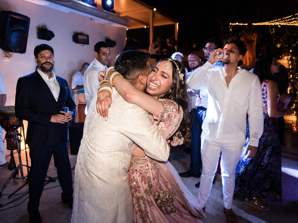 Bride hugging groom on dance floor at Private House Island Resort Indian wedding party.