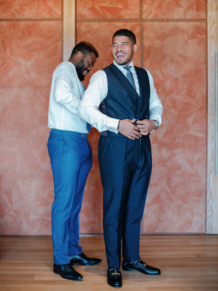 Groom getting ready in navy suit during luxury Nigerian wedding preparation at The Margi Hotel Athens.