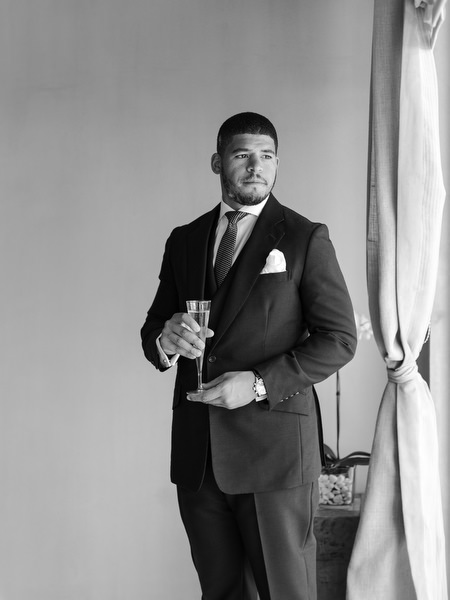 Groom portrait holding champagne ahead of grand Nigerian destination wedding in Athens Greece.