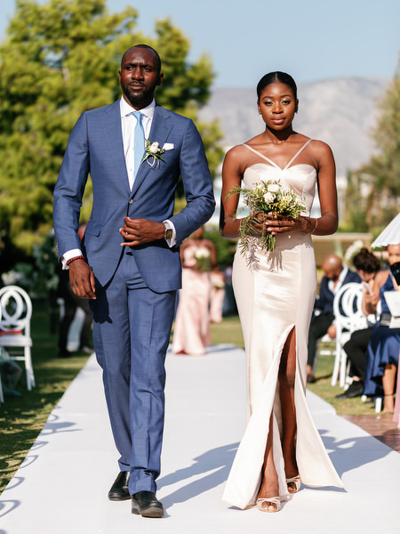 Groomsman and bridesmaid walking aisle at Ble Azure ceremony during high-end Nigerian wedding in Greece.