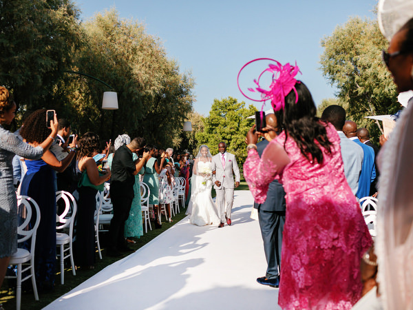 Celebratory guest dancing during Nigerian wedding processional at Ble Azure ceremony in Athens Greece.