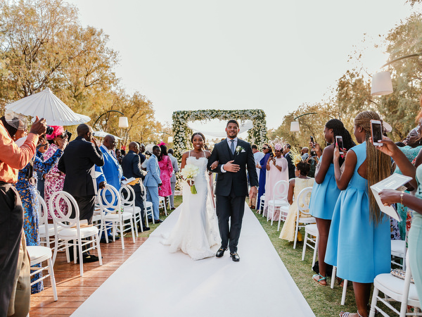 Bride and groom walking down aisle as guests celebrate at Ble Azure Nigerian wedding ceremony in Athens.